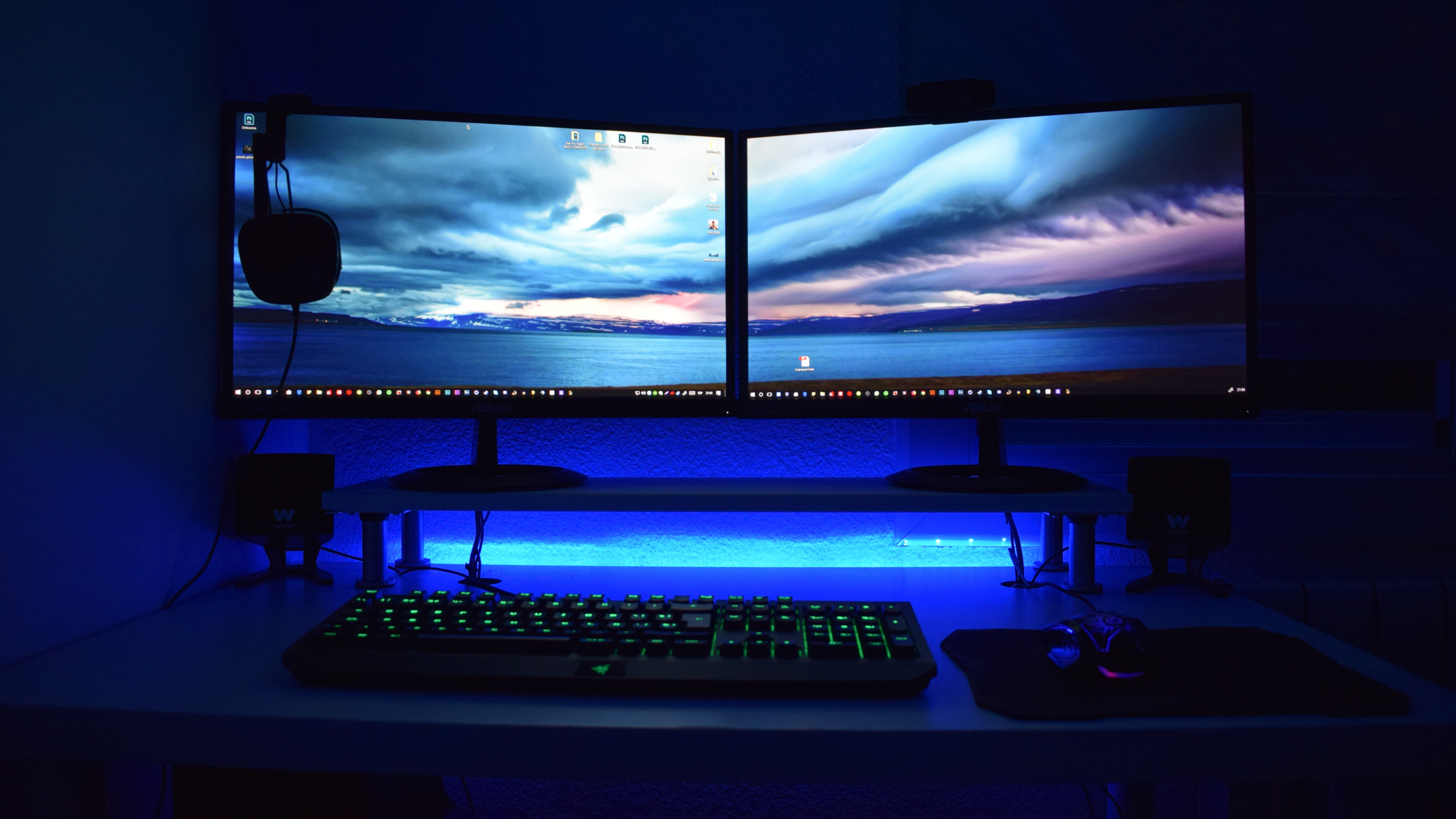 A desk with two monitors, a keyboard, a mouse and a headset.