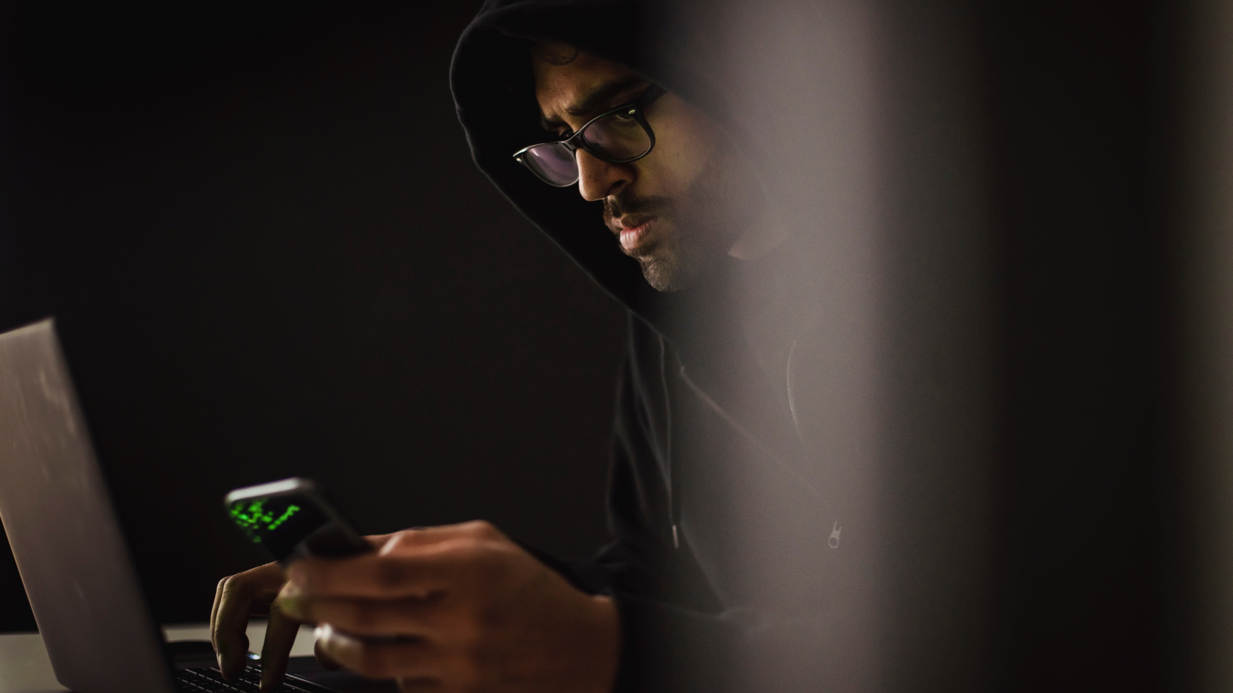 Un homme travaillant sur son ordinateur et son téléphone.